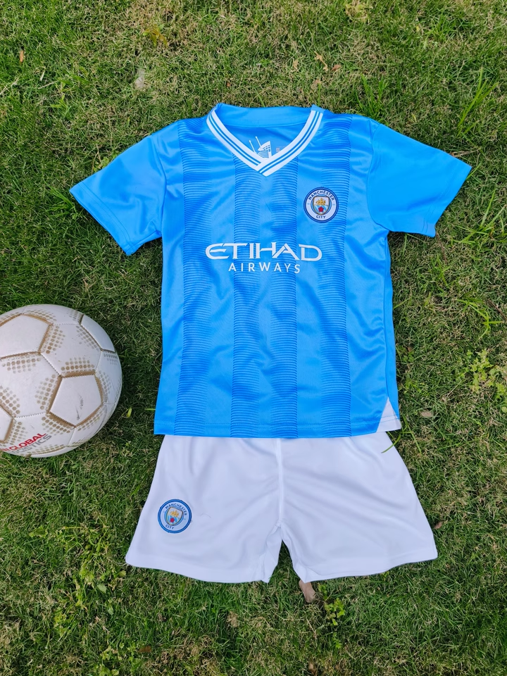 https://www.nogometnizaotroke.com/wp-content/uploads/2025/05/Otroski-Nogometna-dresi-Manchester-City.png